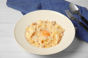 Delicious pasta with egg yolk and cheese on wooden table
