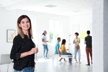 Young woman with glass of champagne at exhibition in art gallery
