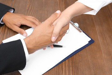 Woman shaking hands with real estate agent on meeting over table