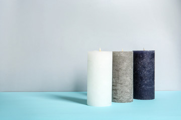 Decorative wax candles on table against light background