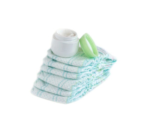 Baby diapers on a white background and a jar with baby cream