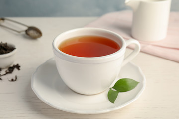 Cup of delicious tea with saucer on table