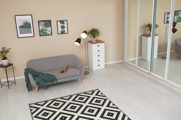 Stylish light room interior with comfortable gray sofa