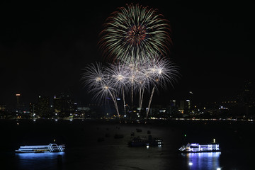 Beautiful fireworks with night cityscape and cruises in the sea