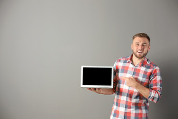 Portrait of handsome man with laptop on color background