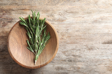 Plate with fresh rosemary twigs on wooden table, top view