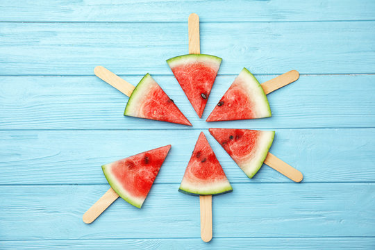 Flat lay composition with watermelon popsicles on wooden background