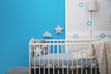 Baby room interior with crib near color wall