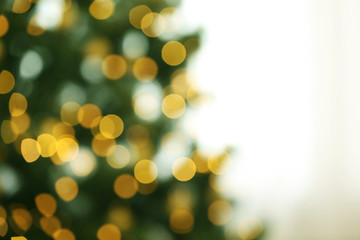 Fototapeta na wymiar Blurred view of fir tree with glowing Christmas lights indoors. Festive mood