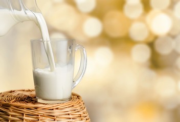Glass jug of fresh milk on background