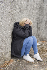 Upset young woman in twenties, outdoors siting on the ground