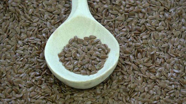 Rotating wooden spoon on flax seeds background 
