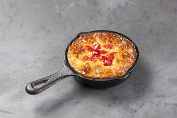 Individual mini quiche pie in a cast iron pan on a grey slate effect surface