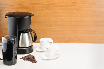 Coffee machine with pot and handful coffee beans on the wood and marble background. Copy space.