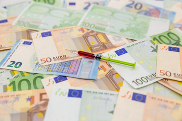 Spread Stack of Euro Banknotes with syringe on top of them, health costs concept