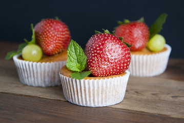Fresh Strawberry fruits with homemade muffins over wooden table and black background decorated with mint leaves. Copy space. Banner. 