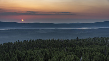 Rising sun behind hill between clouds. Sunrise in the mountains.