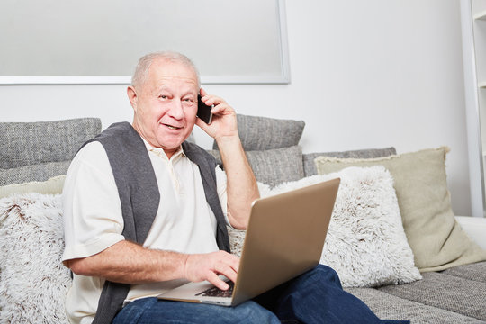 Älterer Mann mit Smartphone und Laptop