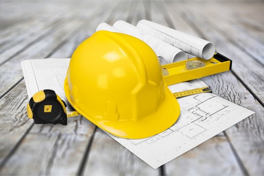 Yellow hard hat and blueprints on wooden