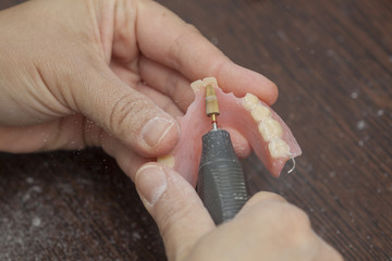 Dental technician make denture prothesis with motor tool in dental laboratory