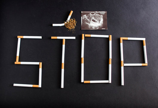 The word stop is laid out with cigarettes on a black background, next to it is a photograph of the pregnancy uzi, pregnancy and smoking, pregnancy and smoking