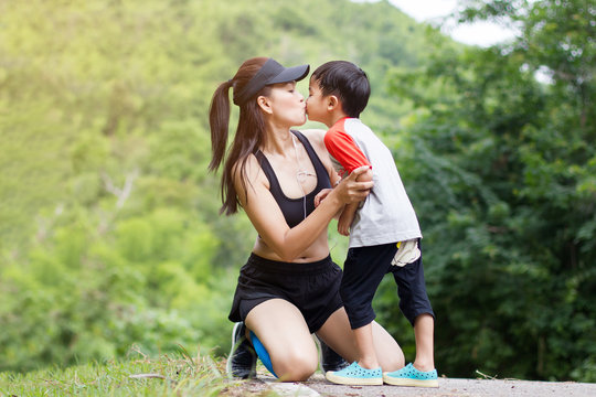Young mother wear sport cloth kiss her son boy at nature outdoors.Concept image healthy family.