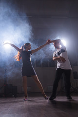 Skillful dancers performing in the dark room under the concert light and smoke. Sensual couple performing an artistic and emotional contemporary dance