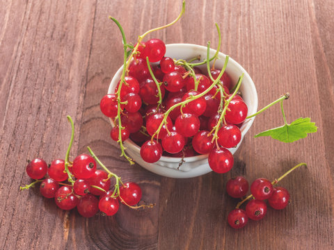 Fresh red currant in white ceramic plate on wood background