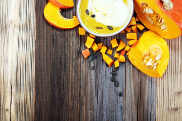 Roasted pumpkin and carrot soup with cream and pumpkin seeds on table.