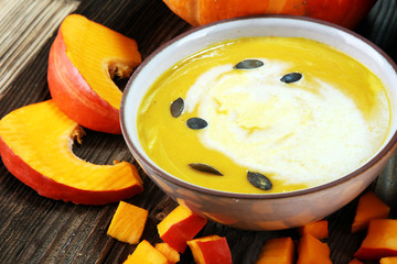 Roasted pumpkin and carrot soup with cream and pumpkin seeds on table.