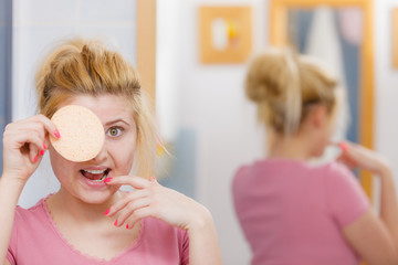 Woman having wash gel on face holding sponge