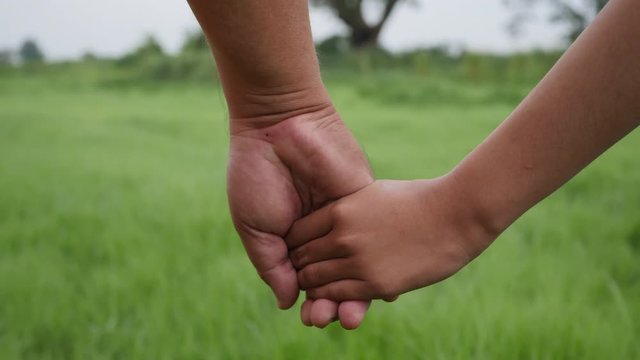 Close up hand of the father holding the daughter hand in slow motion scene