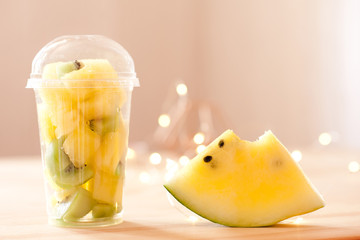 Fresh chopped fruits in plastic up staying on wooden table closeup. Tasty breakfast. Good morning.