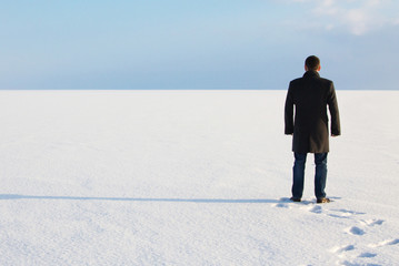 man standing on the shore of a frozen sea downshifting way relaxes on a winter seascape