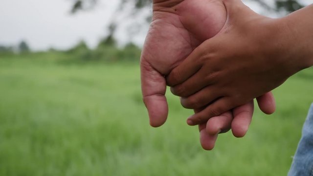 Close up hand of the father holding the daughter hand in slow motion scene