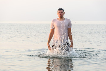 A young man jumps out from under the water with splashes
