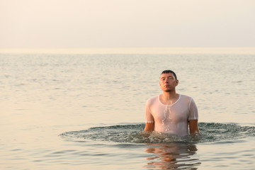 A young man jumps out from under the water with splashes