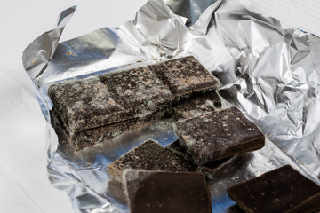 Moldy chocolate in the original packaging. Out-dated food products used for desserts.