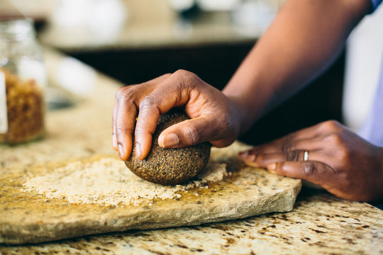 African-American Woman's Hand Crushing Ingredients with Grinding Stone