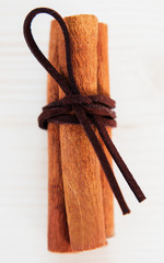 Cinnamon with brown ribbon. Closeup on wooden background