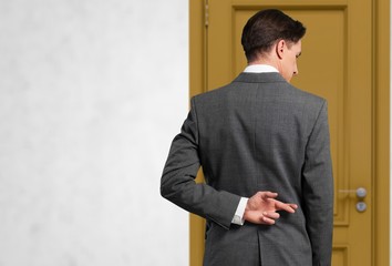 Businessman with his fingers crossed behind