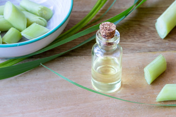 A bottle of lemon grass essential oil with fresh lemon grass