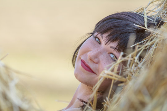 Portrait cute happy beautiful female brunette with red lipstick against a background of wheat field at the time of the sunset
