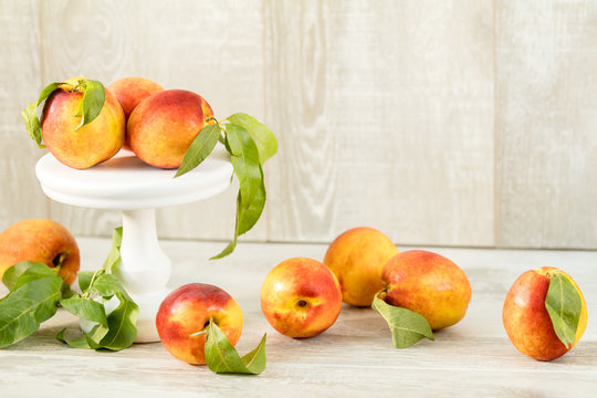 Many juicy beautiful amazing nice peaches on light wooden background. Beautiful food art background.