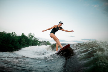 Fototapeta premium Young attractive woman riding on the orange wakesurf