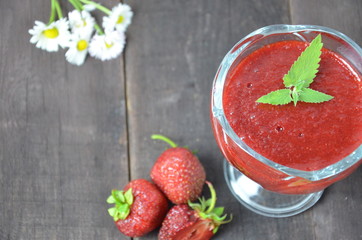 Jars of strawberry jam or jelly with berries and spoon on brown woodwn background close up top view, copy space.