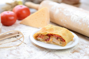strudel with ham and cheese on a wooden board with flour