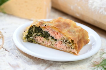 strudel with fish and spinach on a wooden board with flour