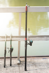 Three fishing rods at the wooden pier under the sun
