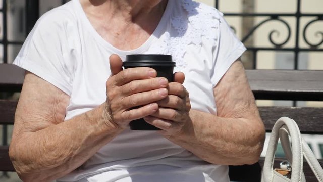 Closeup Of Elderly Woman Holding Coffee To Go